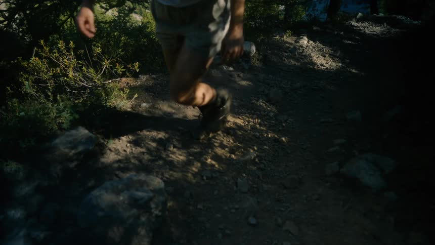 Legs of a person climbing a mountain on a rocky trail
