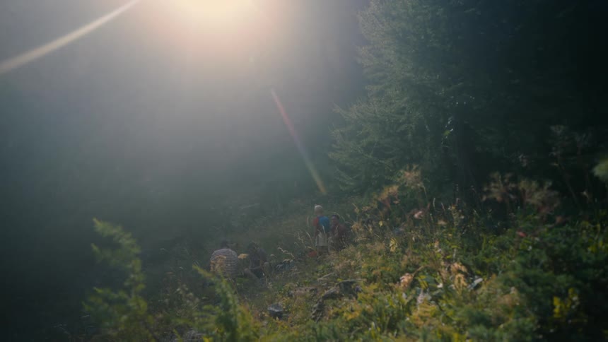 Bright sun glares down onto people in a camp at the base of a hill