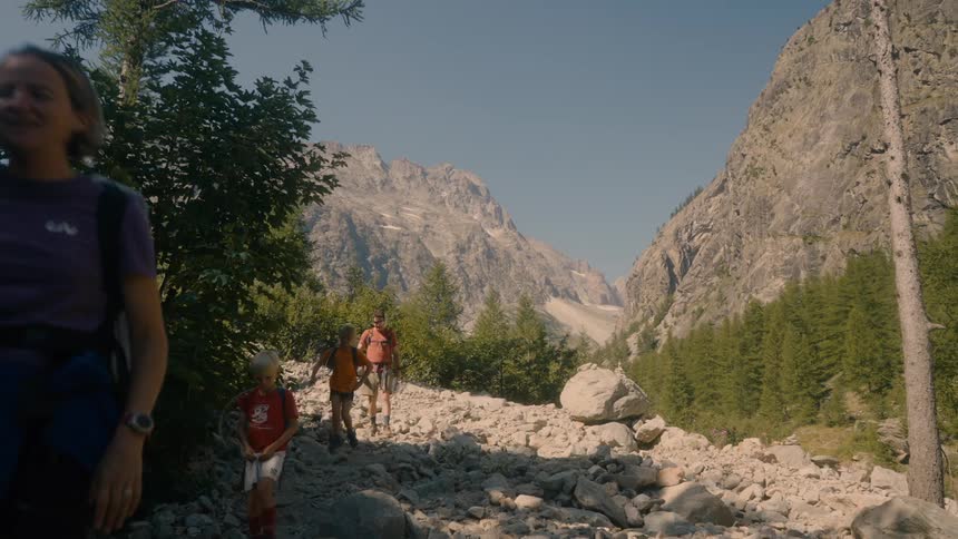 Family hiking through a rocky and coniferous area on a mountain
