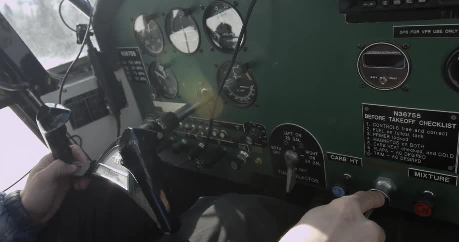 A pilot places his finger over a button on the dashboard