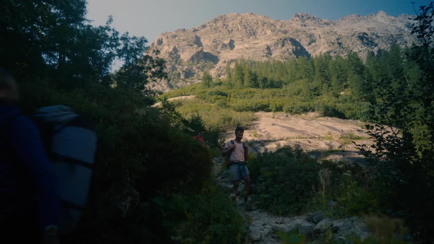 Group of adults and children walking along a treelined trail in a mountain valley setting