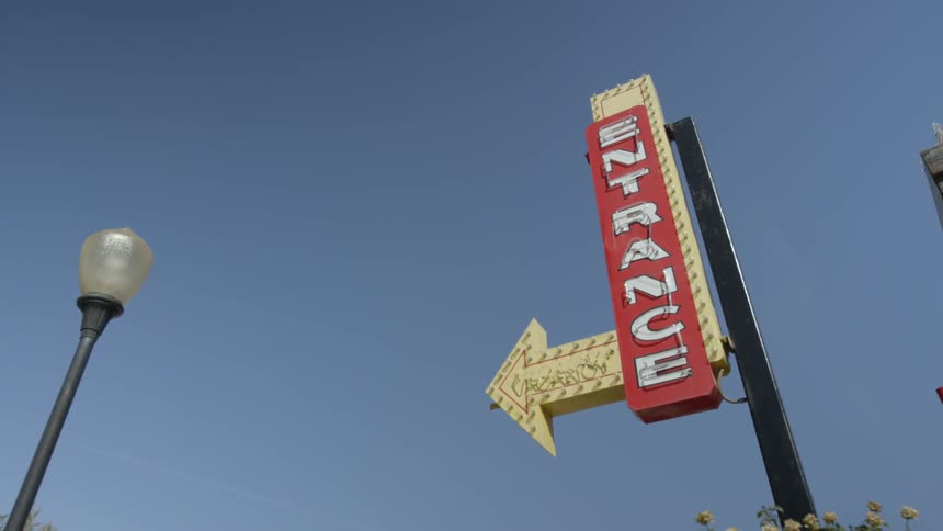 Entrance sign on a city street against a clear blue sky