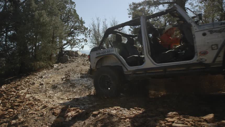 Jeep splashing through muddy water in the woods