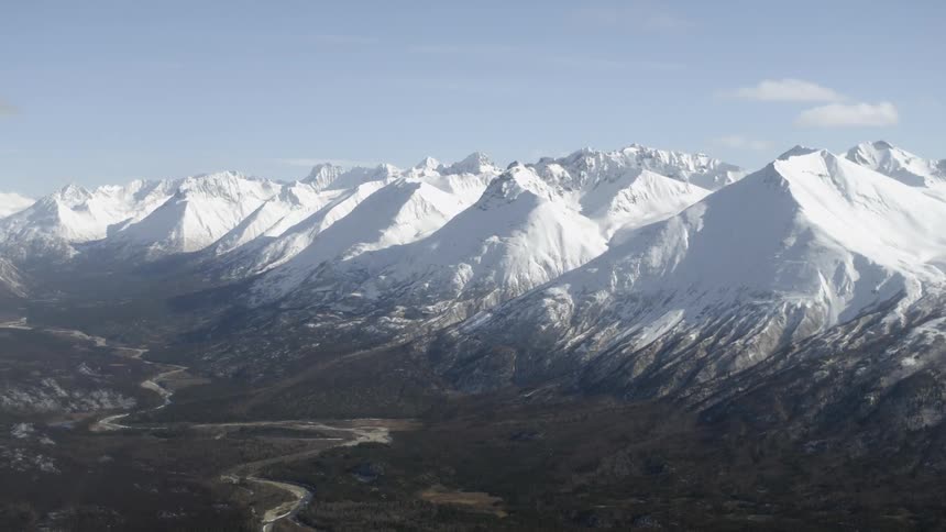 Aerial view of a winding road heading towards some snow-covered mountains