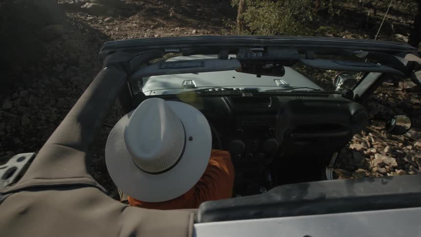 A person drives a jeep along a rocky path in the mountains