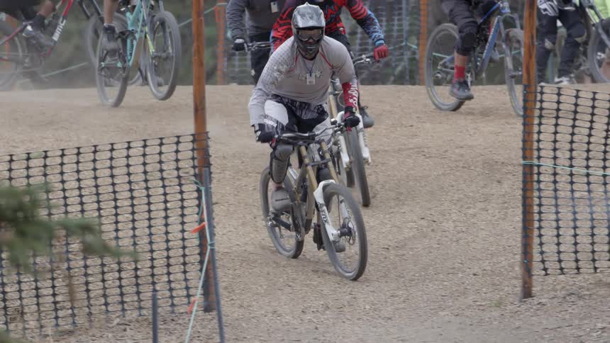 Many people racing on bikes through the sand