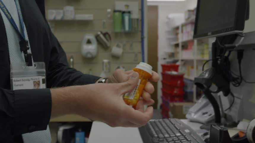 Woman puts a label on a prescription bottle
