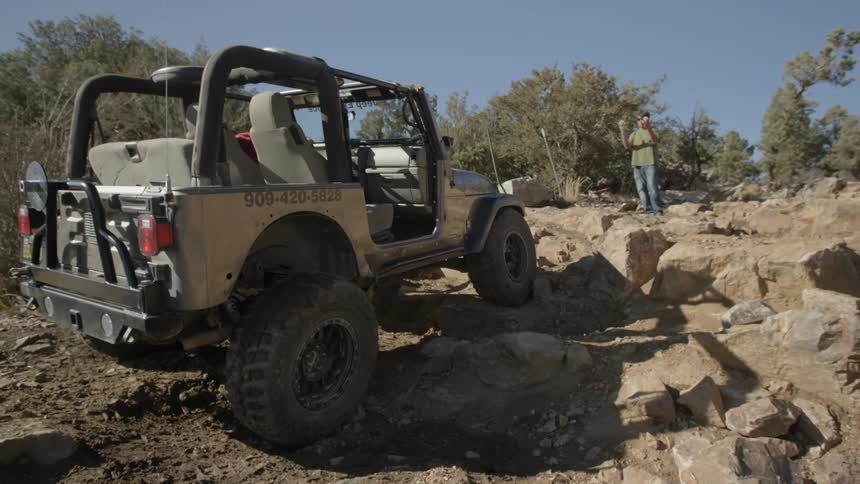 A jeep climbs up a rocky hill