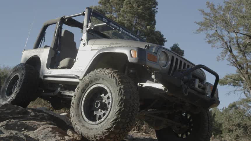 Jeep maneuvering down a rocky incline on a clear day