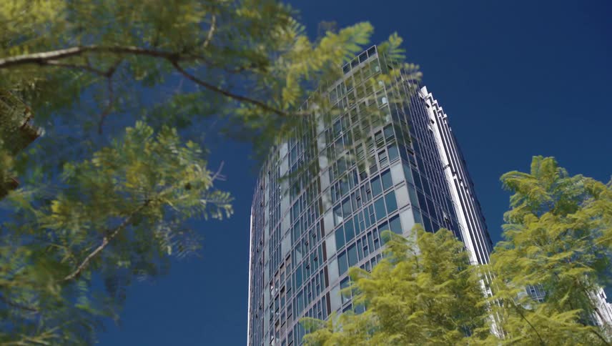 Moving view of a tall modern building against a blue sky
