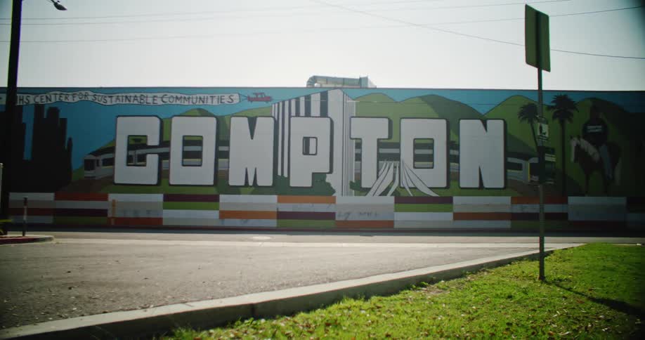 Mural for the city of compton stands at the end of a city street on a sunny day