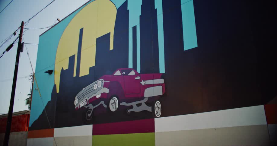 Power lines parallel an urban building decorated with a mural