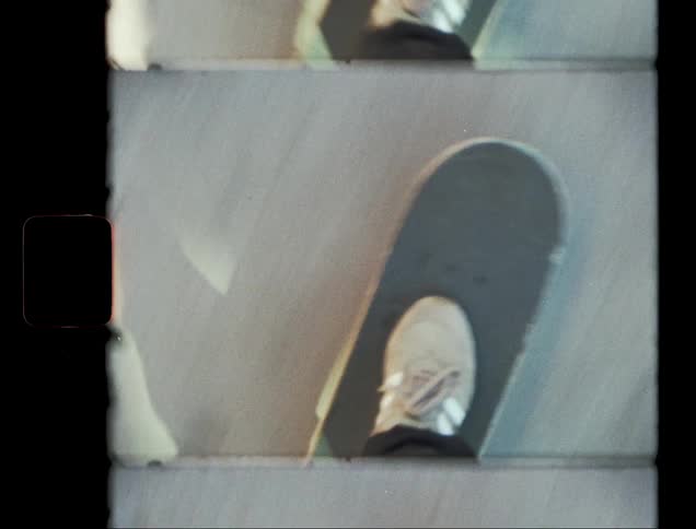 The feet of a person wearing white sneakers who is skateboarding on a concrete floor