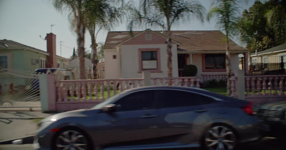 Moving view of an urban neighborhood with parked cars during the day
