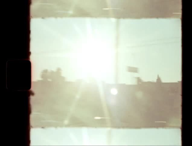 Sun glares down onto traffic passing a strip mall on a summer day