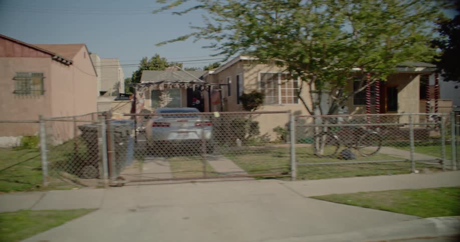 A suburban residential area with several small houses and many cars parked on the street