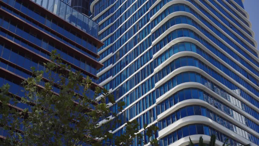 The facade of a large commercial building with its exterior full of glass windows and a rounded corner