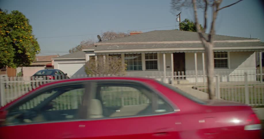 A residential area with several small houses and many cars parked on the street