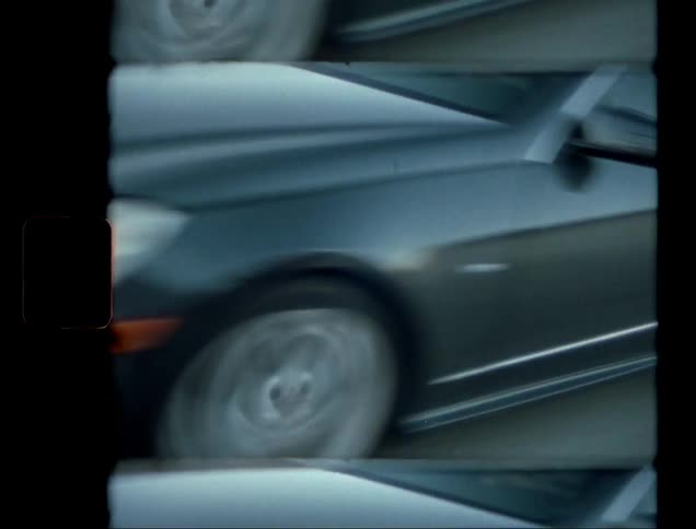 An asphalt street where there is a black car passing quickly