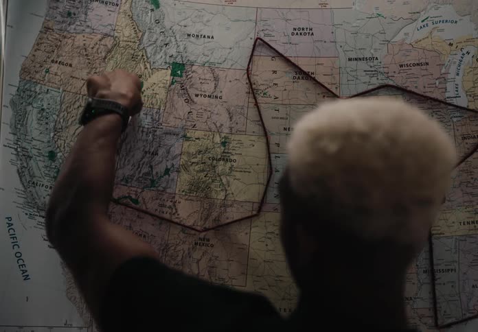 A man traces a route with a thread on a map hanging from a wall