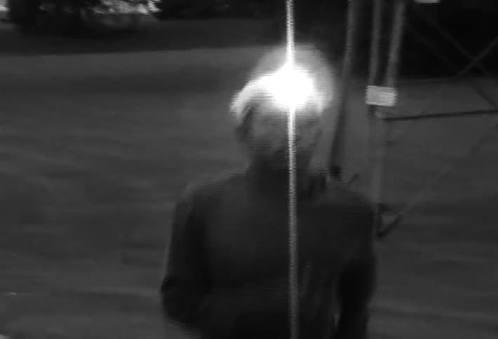 Black and white footage of a man jogging with a headlamp at night