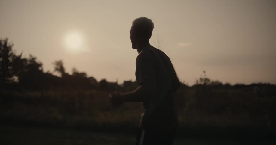 Male jogger runs past a field on a cloudy day