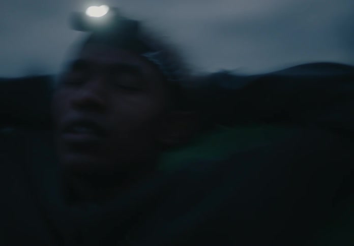 Blurry footage of a person wearing a head lamp outdoors at dusk