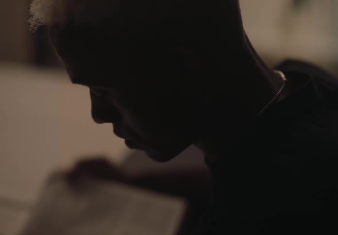 Man wearing a black sweater sits reading a book at night