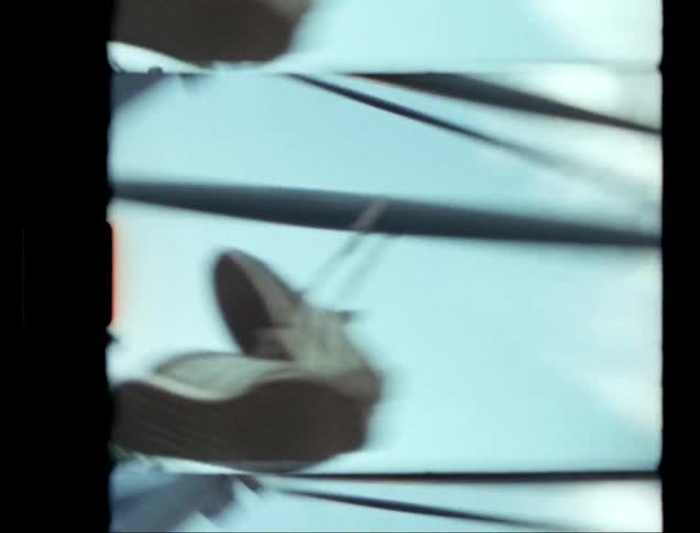 Two white sneakers are attached to a metal frame and spinning