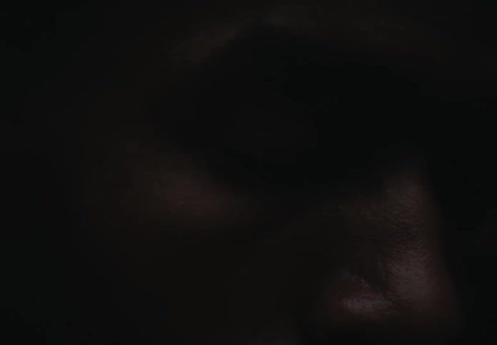 A man opens his eyes as a bright flash of light illuminates his face