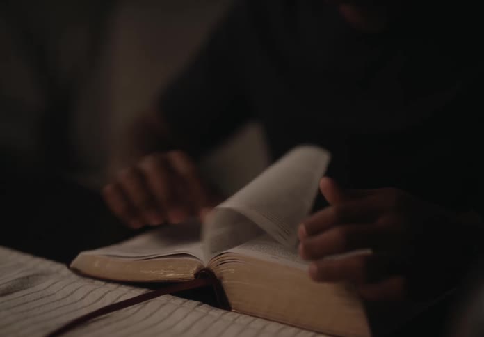 A man is flipping pages in a book while reading