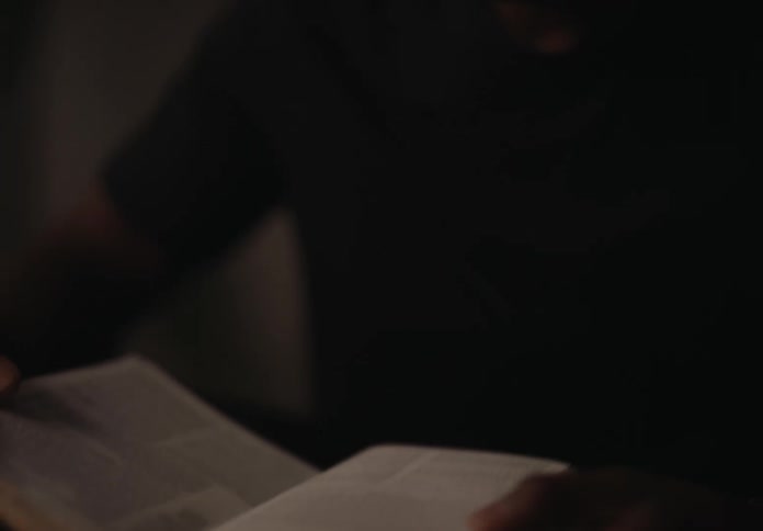 Man sits in a dimly lit room and reads from the bible
