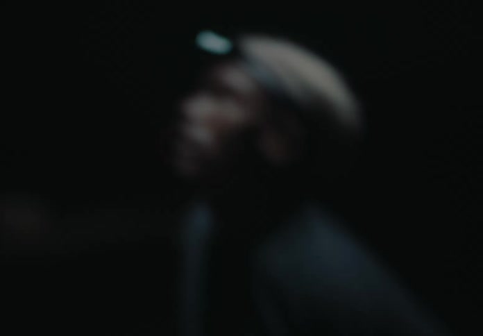 A man wearing a headlight on his head stands in a dark environment illuminating his surroundings