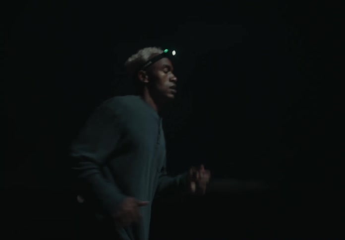 A man is running at night wearing a headlamp illuminating the dark surroundings