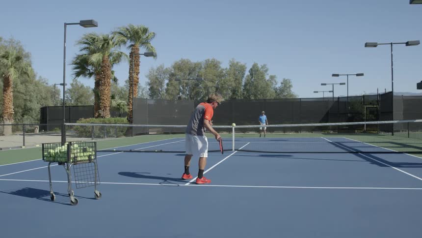 Two people practicing their tennis game on a clear day