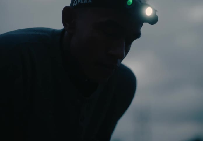 A man stands tiredly after jogging in the morning with a headlamp on