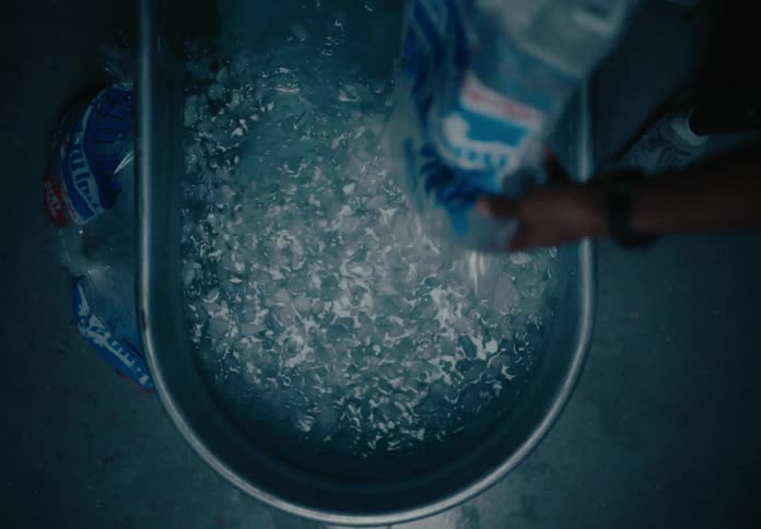 Person pouring ice into a tub of water
