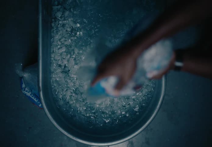 A man pours ice into a tub of water