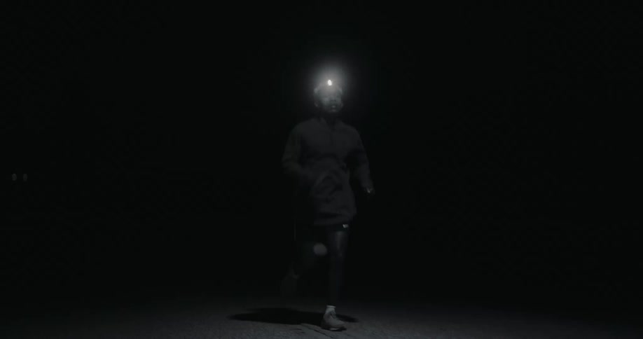 A man running in the dark illuminated by a headlamp