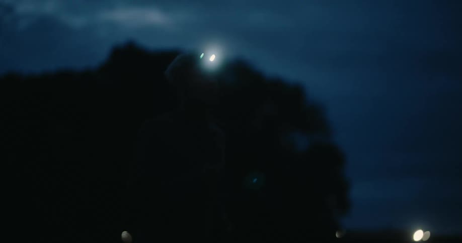 Man with lightcolored hairand a headlight running outdoors at night