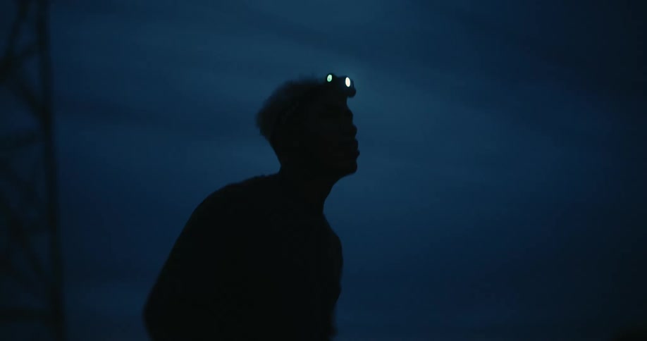 The silhouette of a person running with a flashlight attached to his head at night