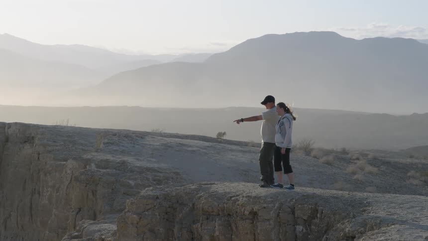 A man and woman overlook a rocky cliff