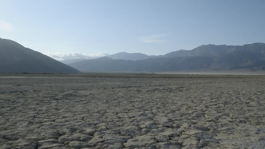 Cracked dry land leading to mountains on a clear day