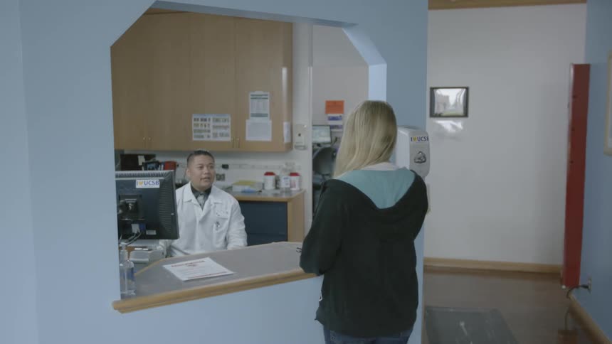 A woman approaches a reception desk in a clinic