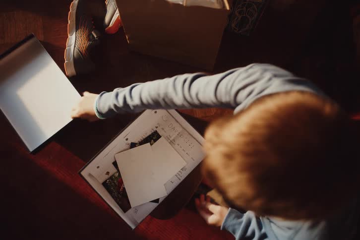 A boy puts several papers in a box and then covers it and takes it to another place