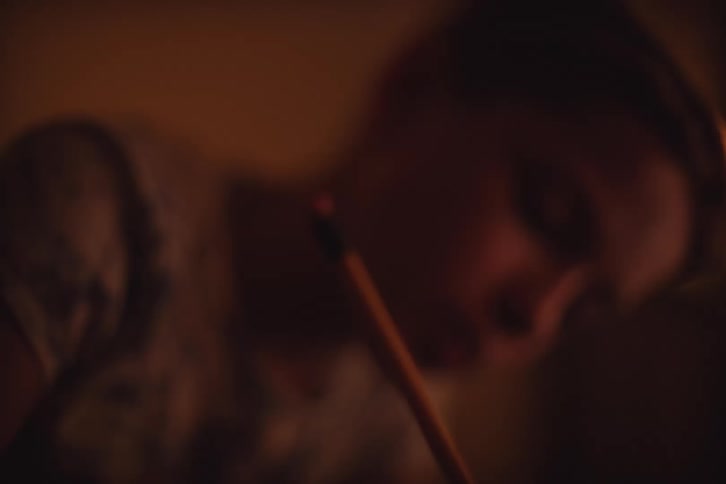 Boy writes while sitting at home in a dimly lit room