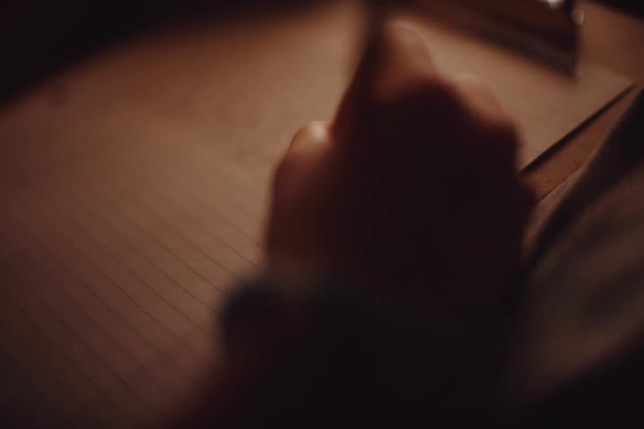 A person is writing on a clipboard