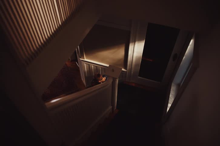 Boy sits near a staircase reading a letter and looking through photographs