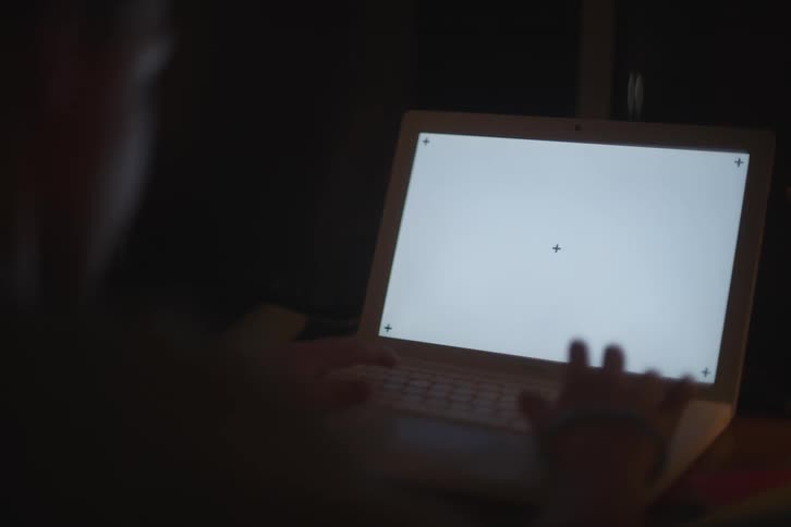 Boy typing on a laptop in a dark room