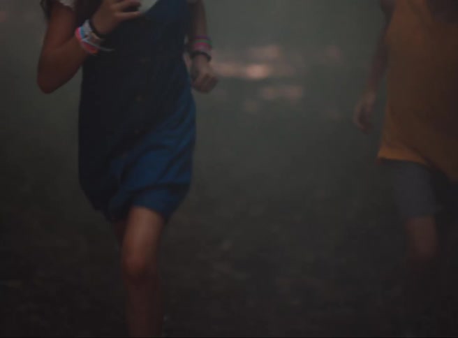 A boy and a girl are running in the forest and there is a white fog in front of them